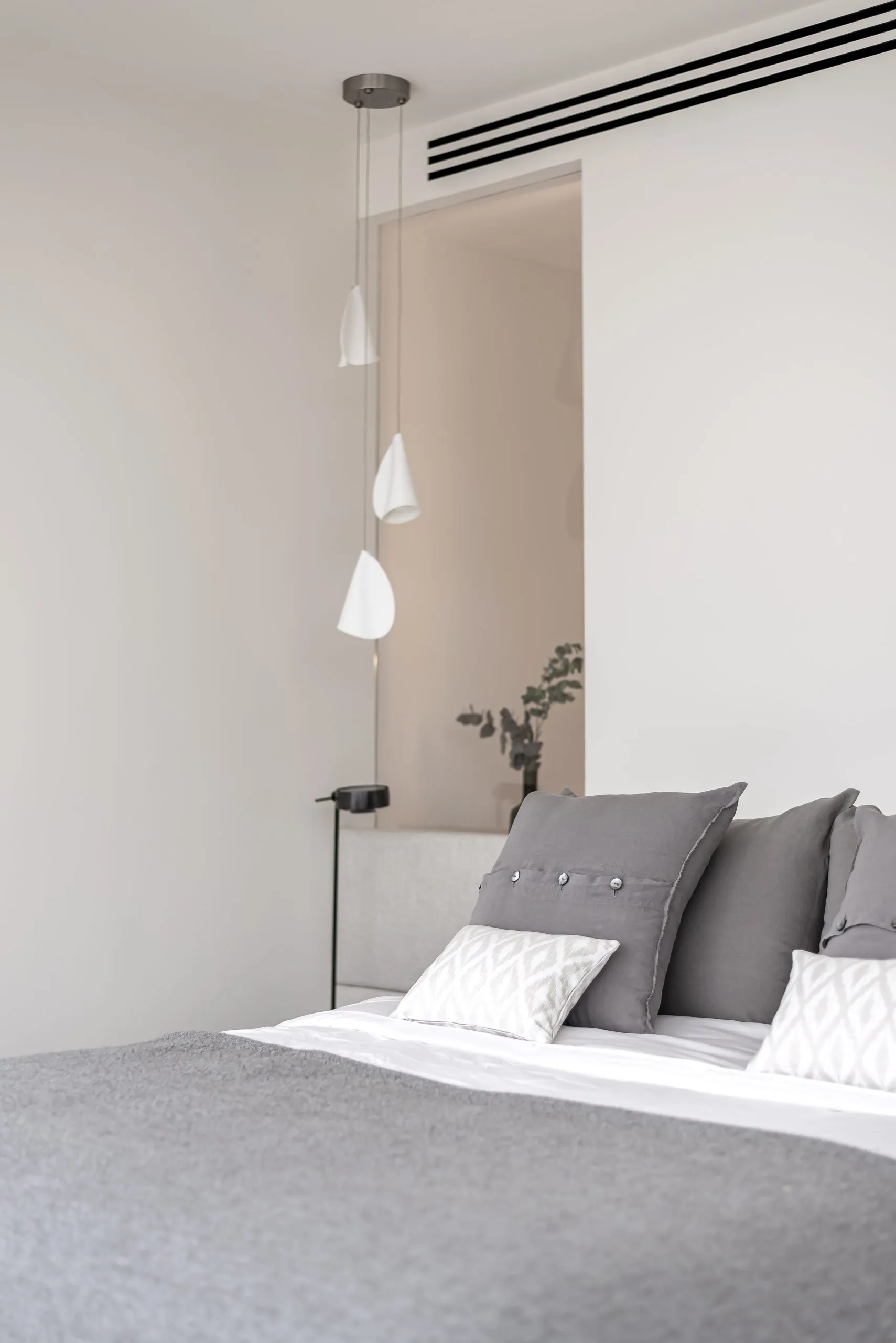 Modern minimalist bedroom featuring grey and white textiles and cotton materials.
