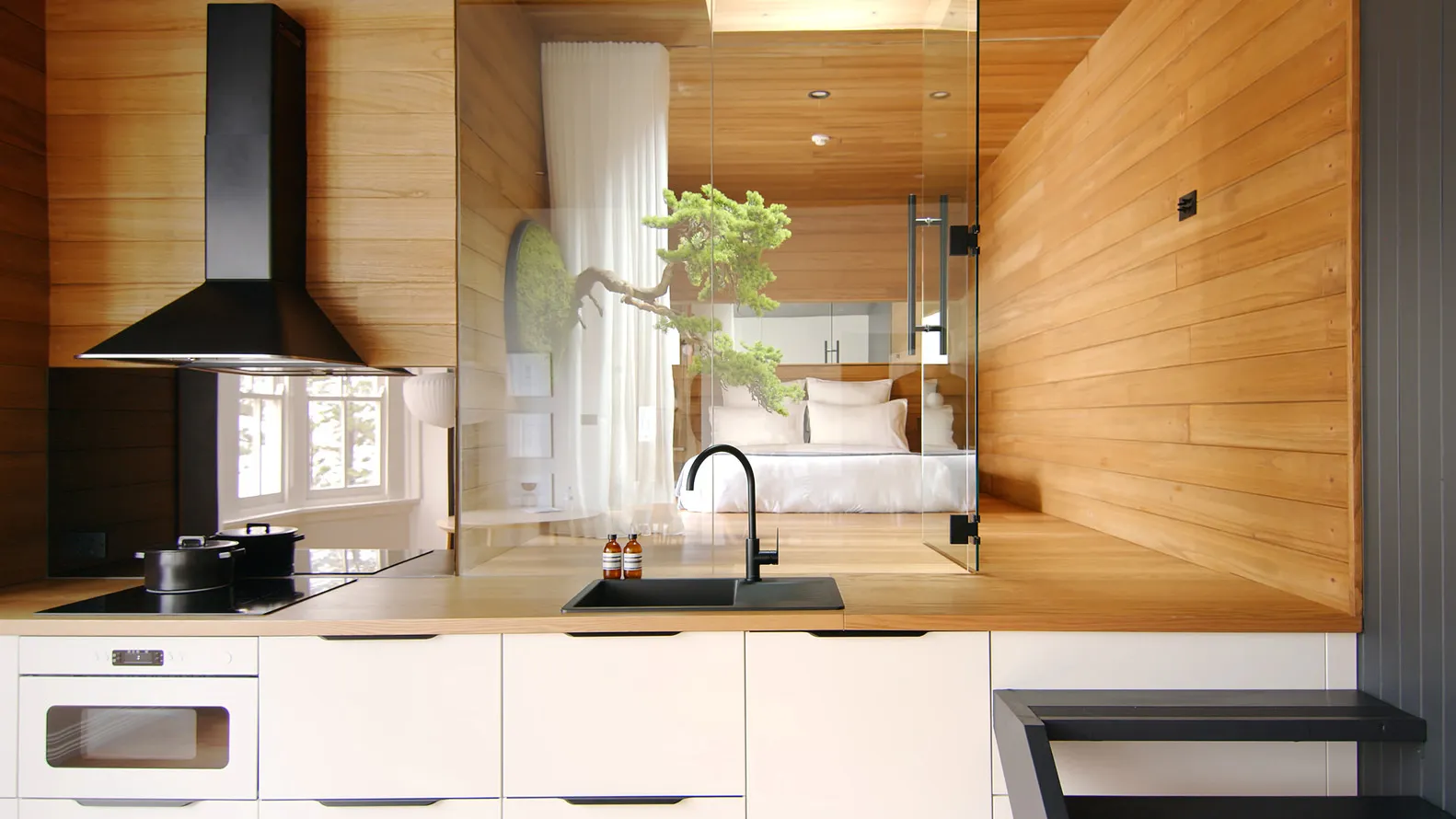 Modern minimalist kitchen with wood finishes and black appliances.