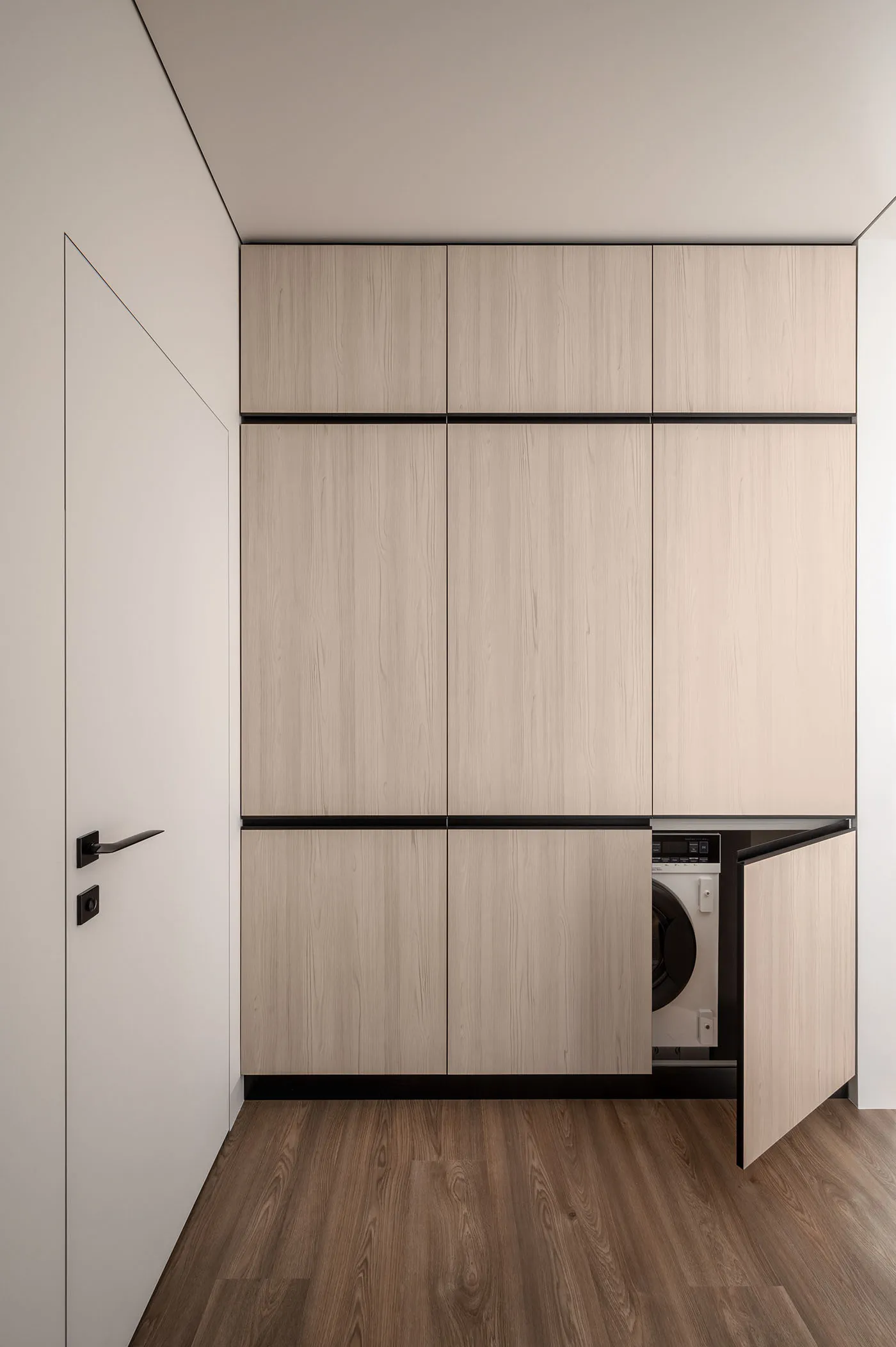 Modern laundry room featuring minimalist, wood-cabinet design for functional and stylish utility space.