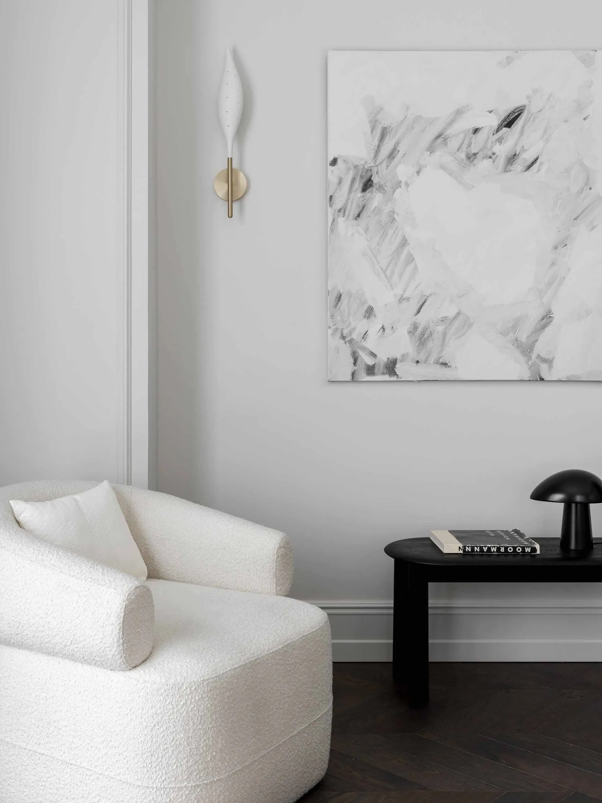 Minimalist living room featuring a textured plush armchair, abstract black and white artwork, black side table, and sleek bla