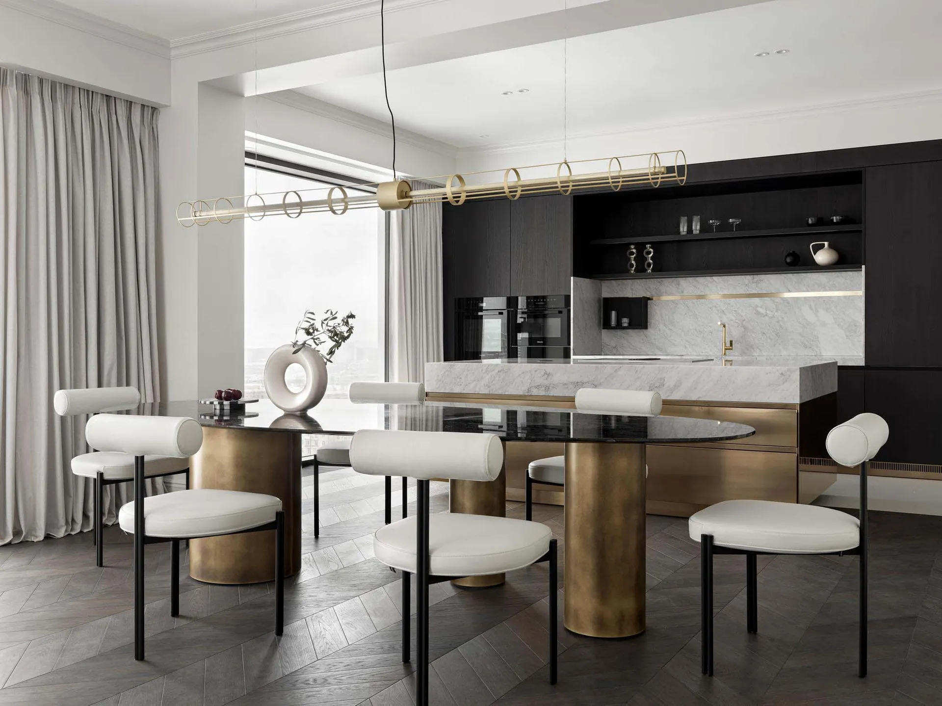 A modern kitchen featuring a white marble countertop, brass accents, and glass elements.