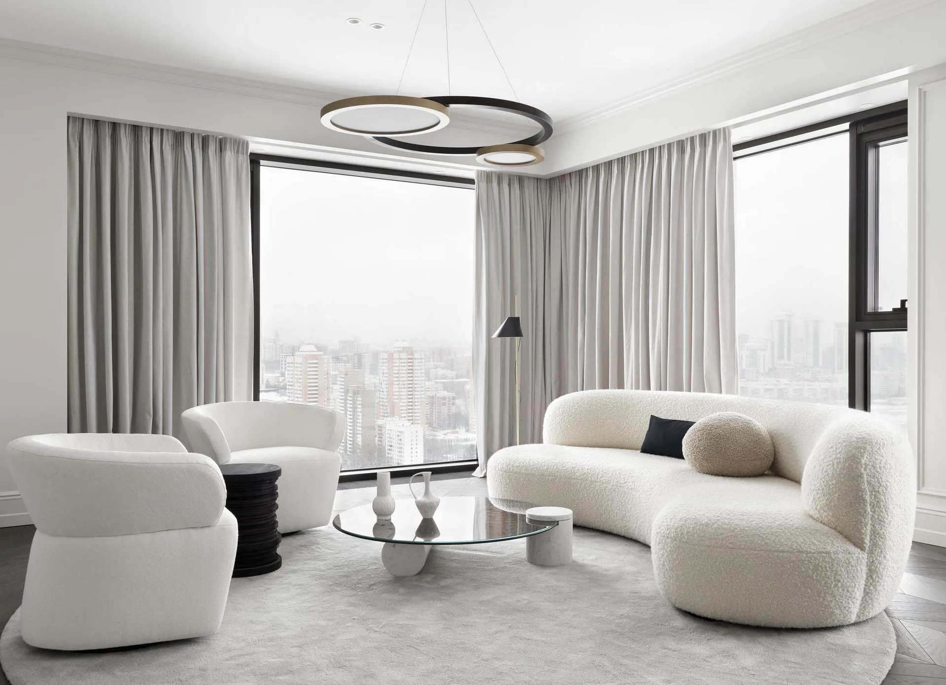 Modern living room with white fabric furniture and a circular coffee table.