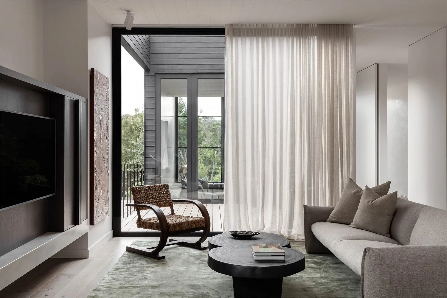 Modern minimalist living room featuring textured cotton sofa, round coffee tables, and large curtains.