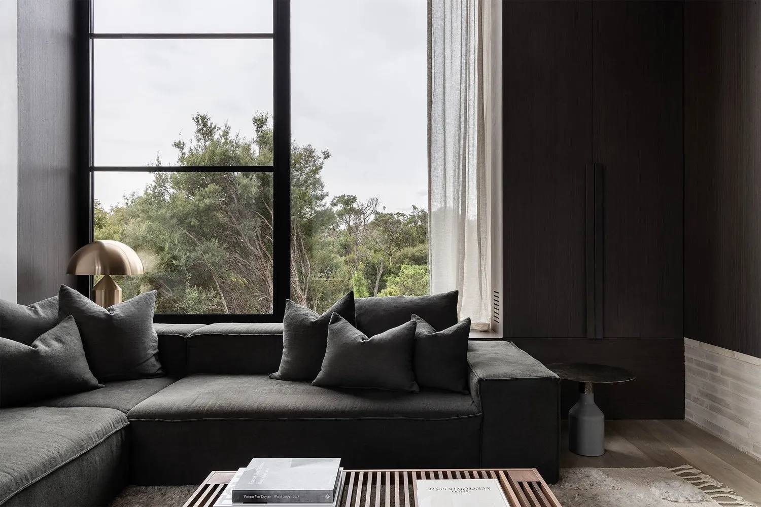 Modern living room featuring a black sofa with grey pillows.