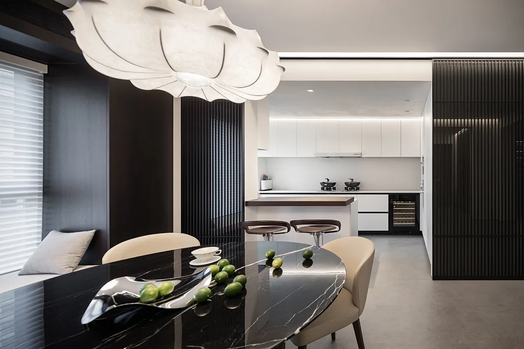 Modern kitchen with a marble countertop and black marble dining table with green limes on it.