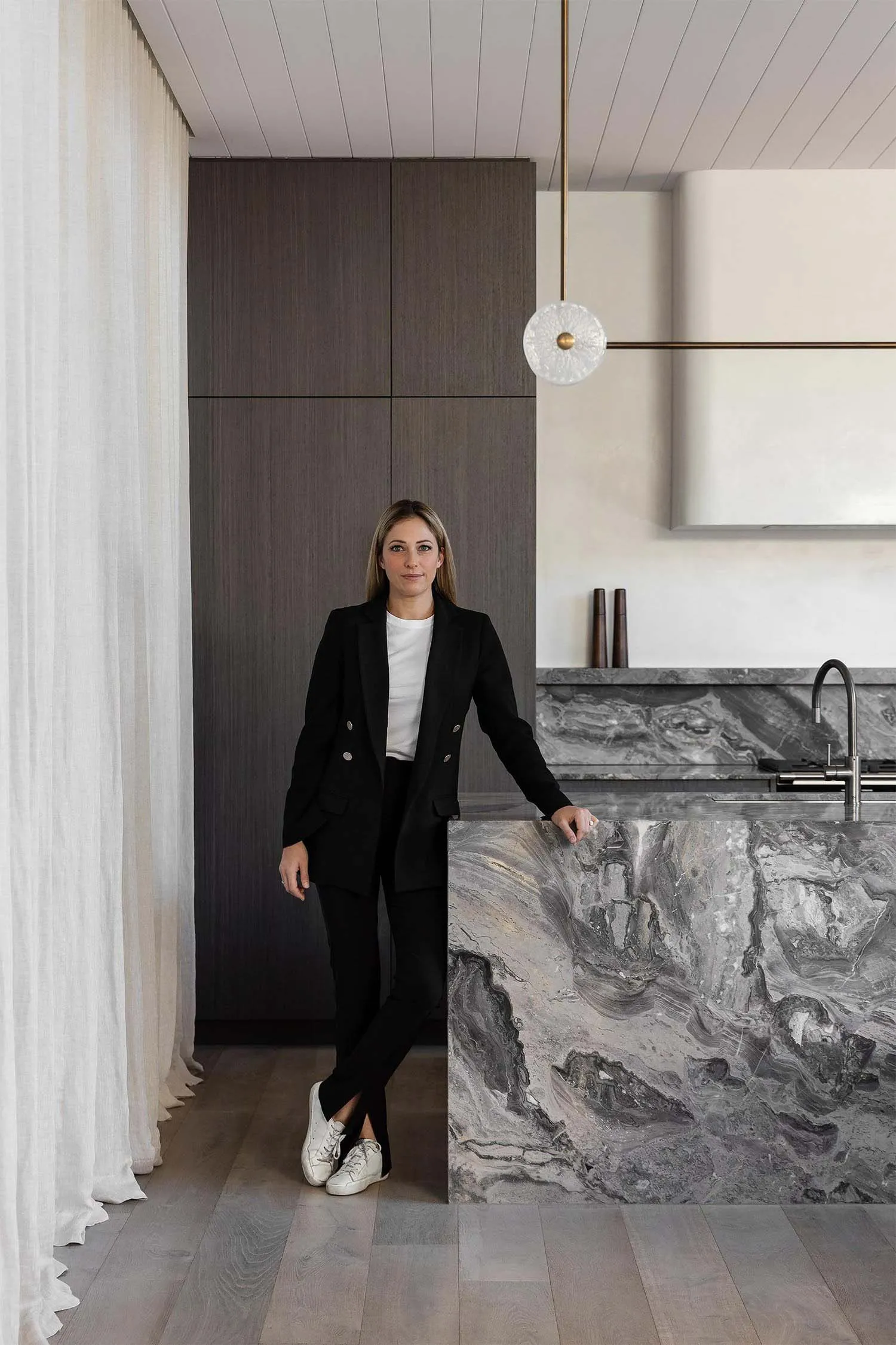 A modern residential interior featuring a kitchen with marble countertops and dark wooden cabinets.