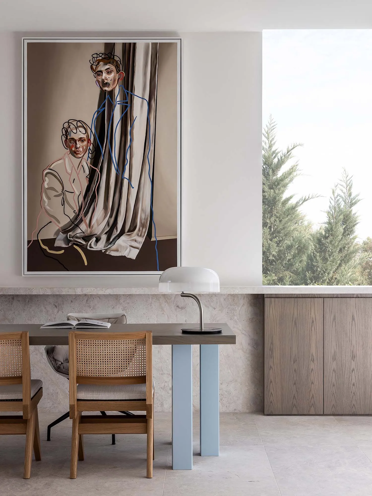 Modern dining room with wooden chairs and a marble table, featuring a fabric curtain and abstract artwork.