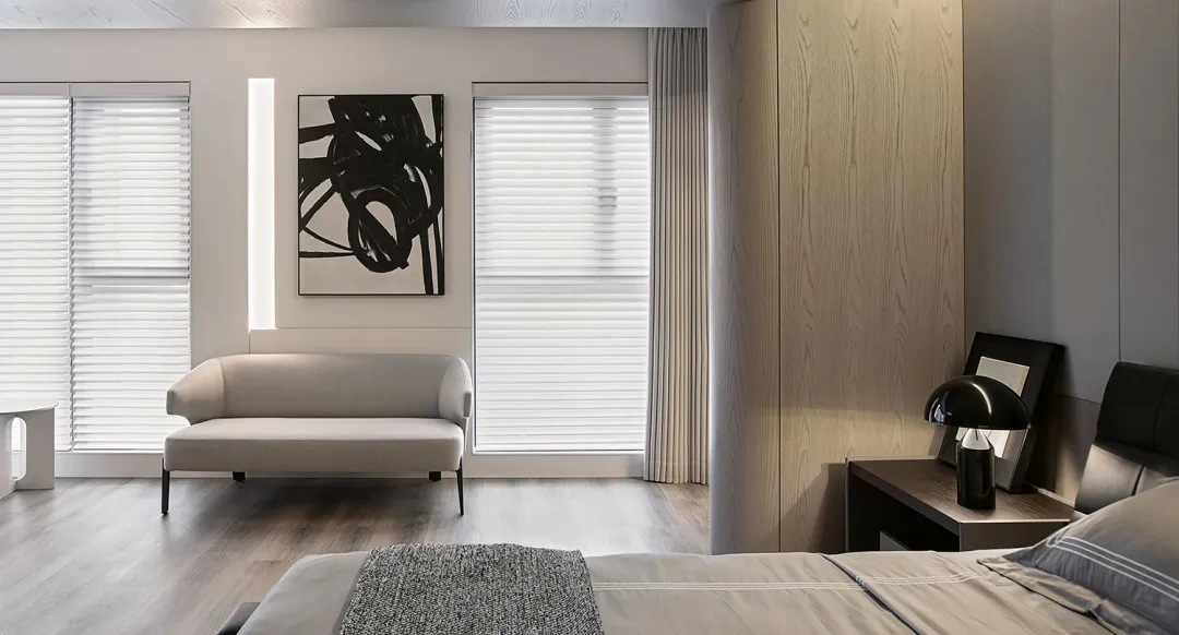 A modern living room featuring a white couch and a minimalist art piece on the wall.