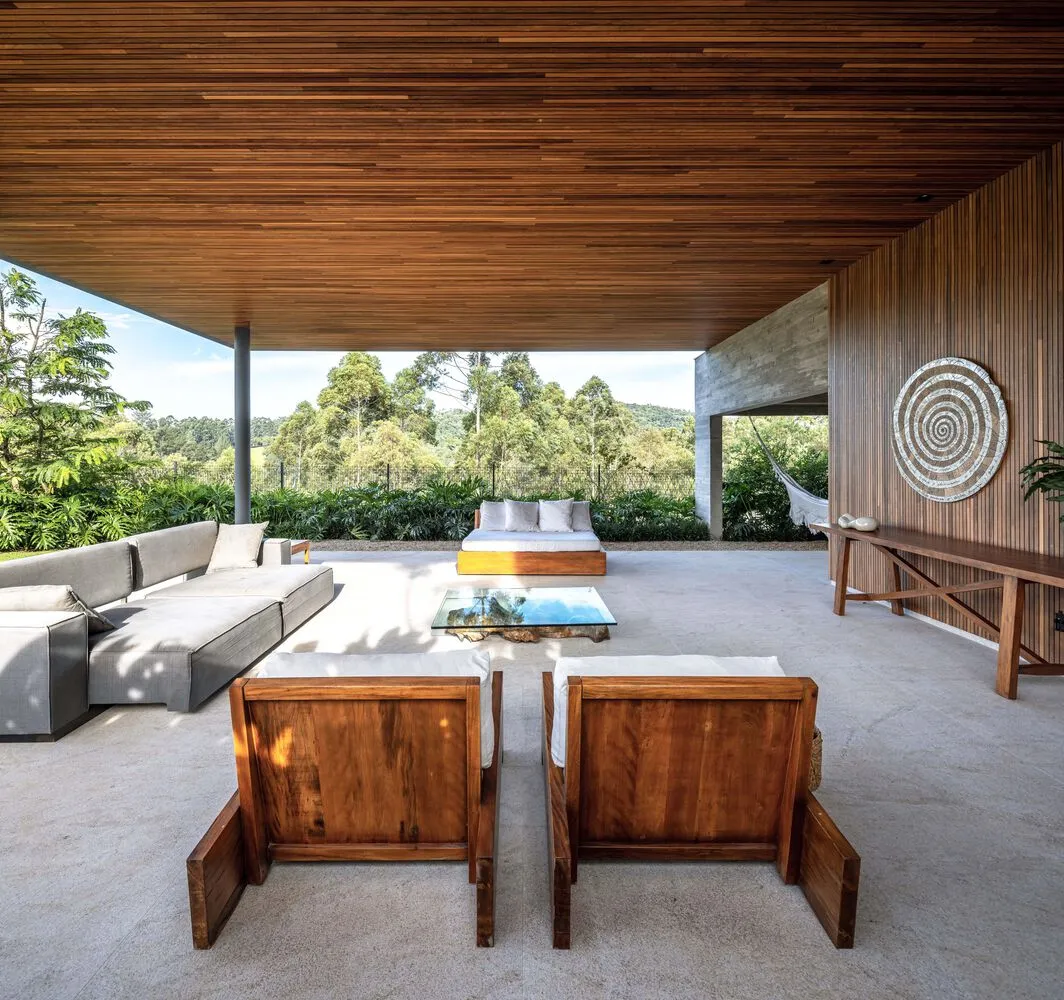 Modern outdoor living space with wood furniture and natural surroundings.