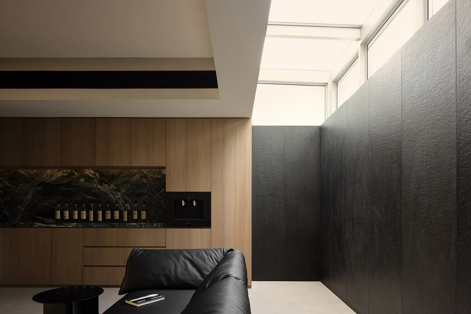 A modern living room featuring wood-paneled walls and black marble accents.