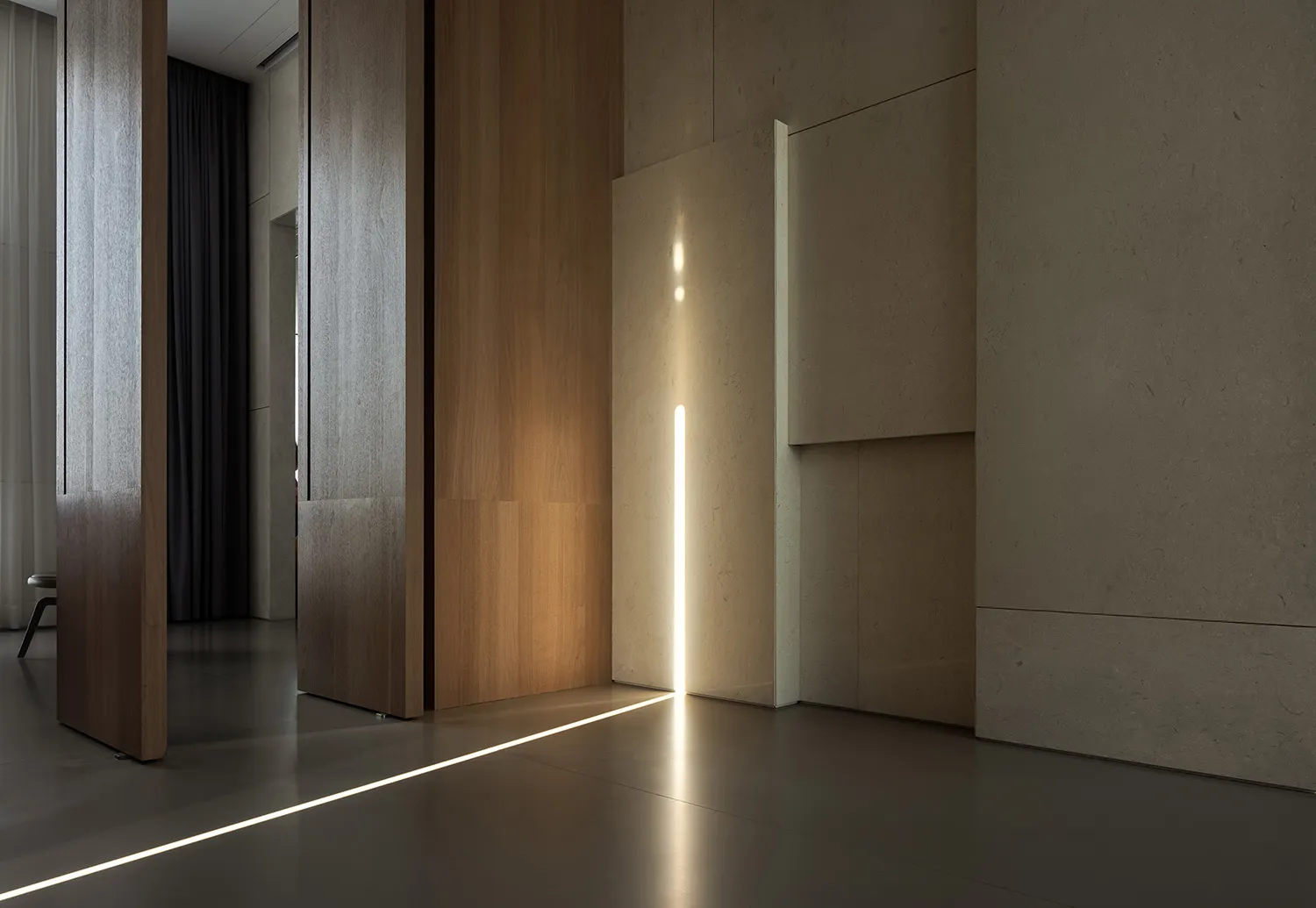 Interior of a modern minimalist living room featuring wooden paneling, concrete surfaces, and a linear light installation.