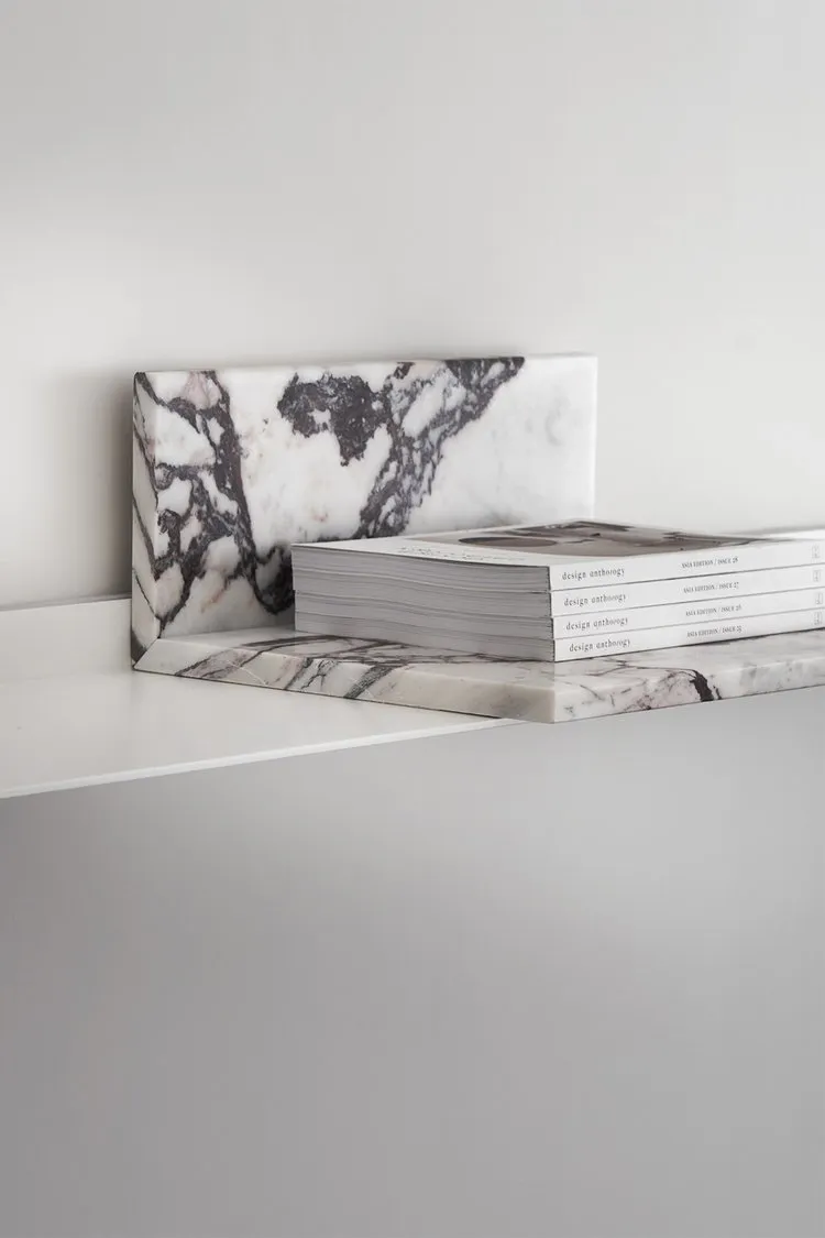 A minimalist marble bookshelf with books.