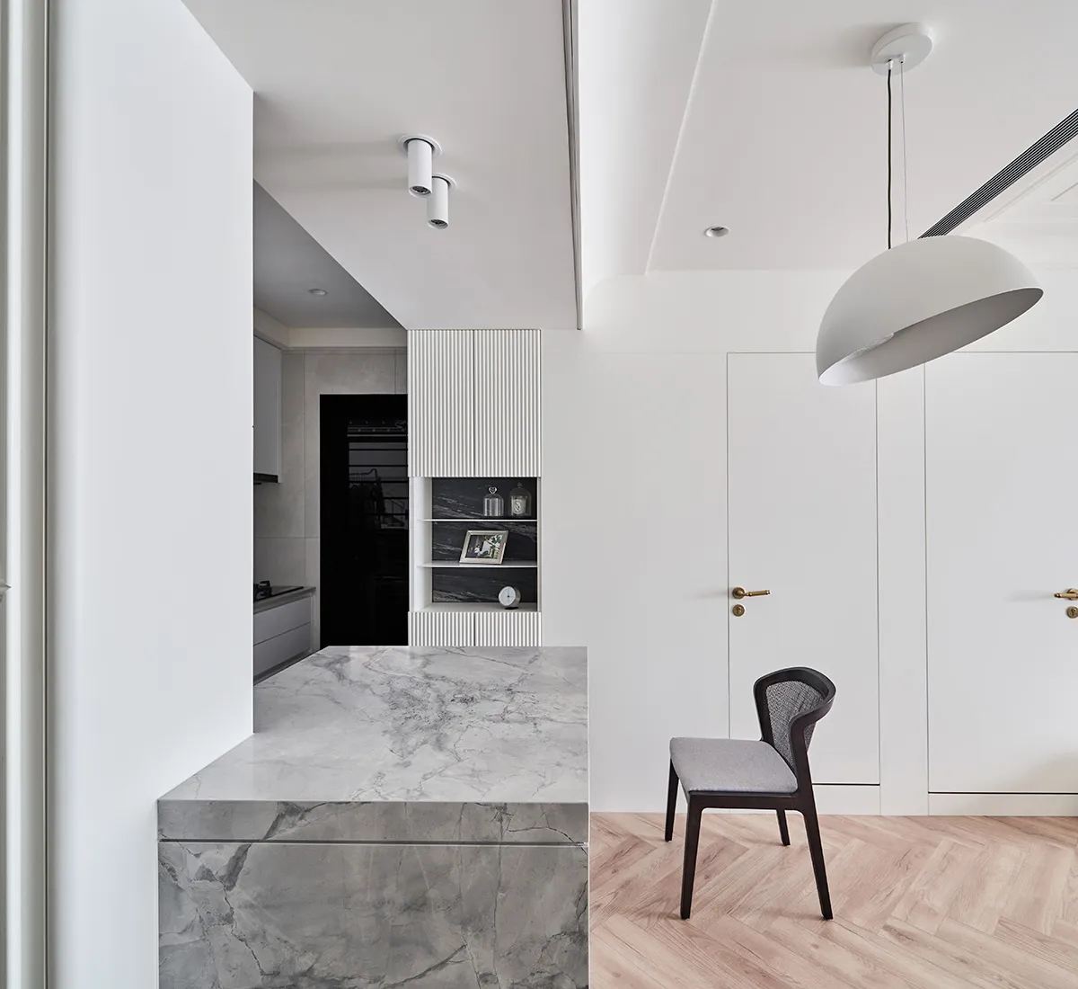 A modern, minimalist residential kitchen with a marble countertop.