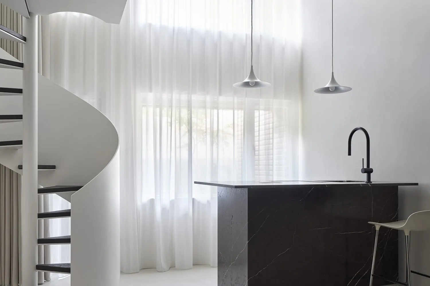 Modern minimalist kitchen with marble countertop and pendant lights.