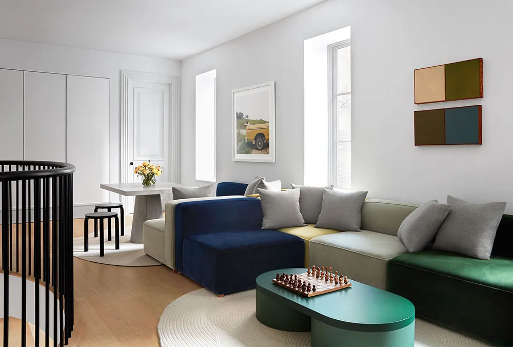 A modern living room featuring a sectional sofa with textured upholstery in shades of blue, beige, and green, placed on a rou