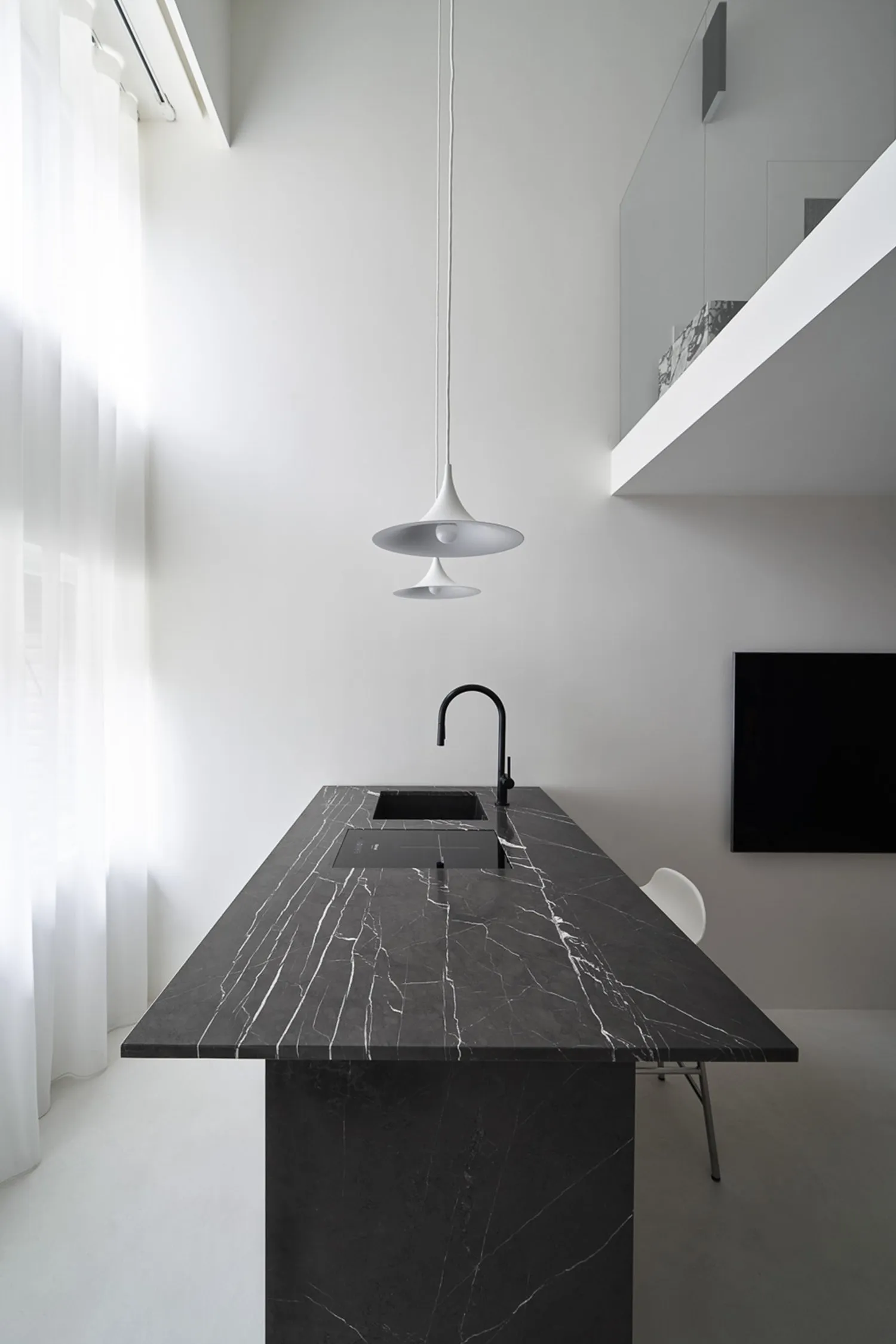Modern minimalist kitchen with black marble countertop and white pendant lights.