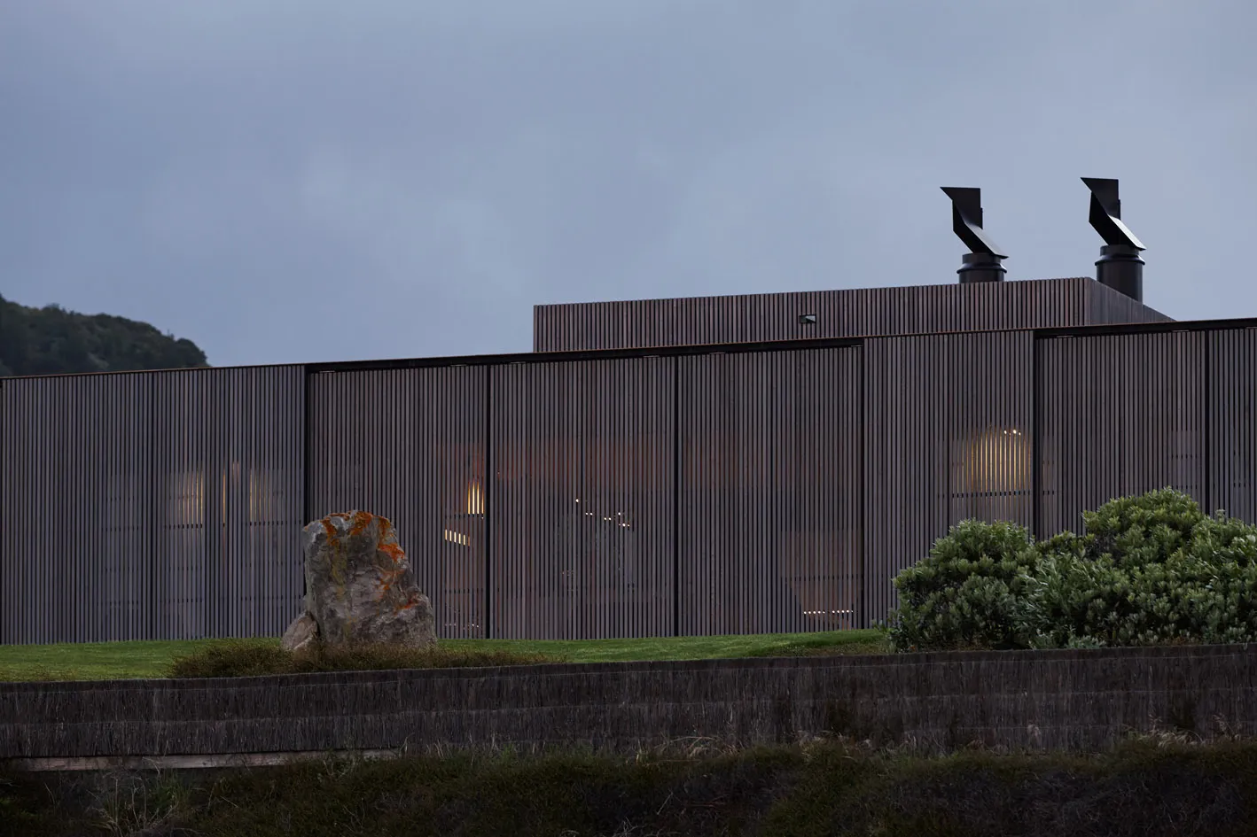 Modern residential exterior with metal cladding and illuminated windows.