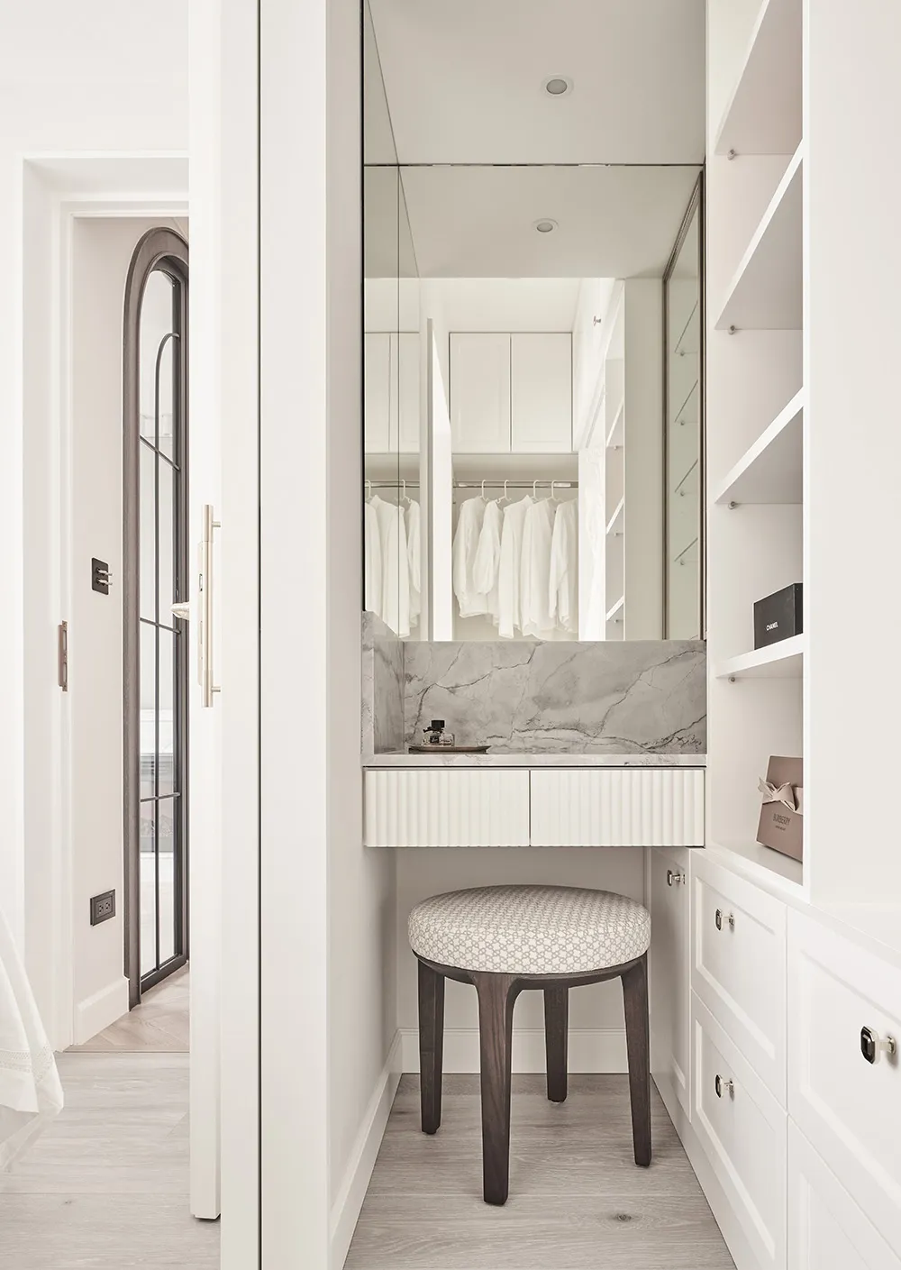 A modern closet with white marble counter and wooden stool