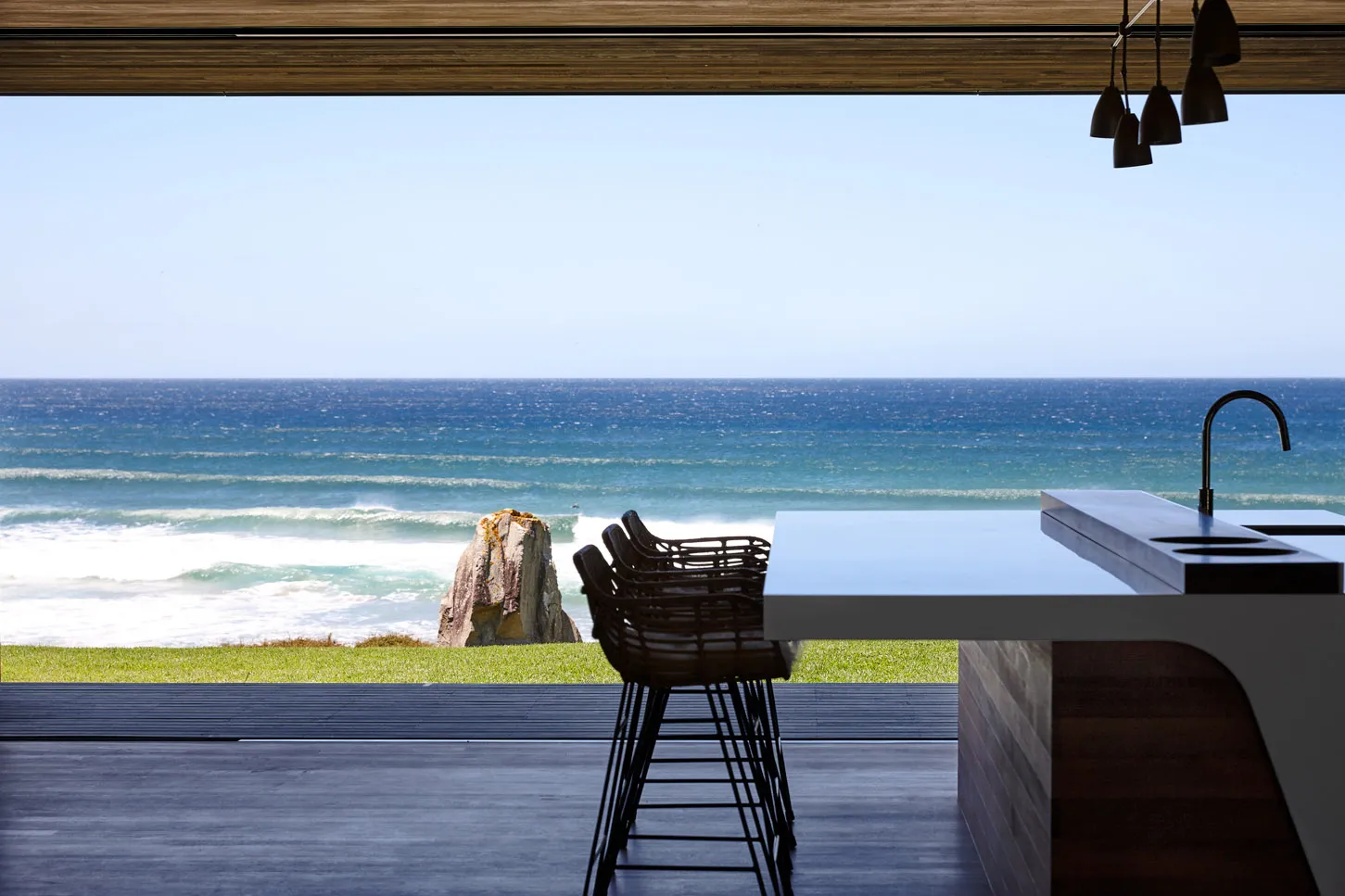 Modern kitchen with ocean view, featuring wood materials and sleek design.