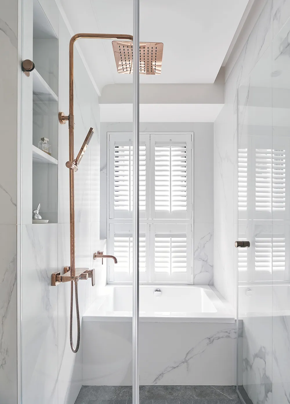 A modern minimalist bathroom featuring marble fixtures and a white bathtub with a window view.