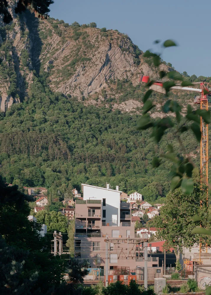 A view of buildings against a mountainous backdrop with lush greenery.