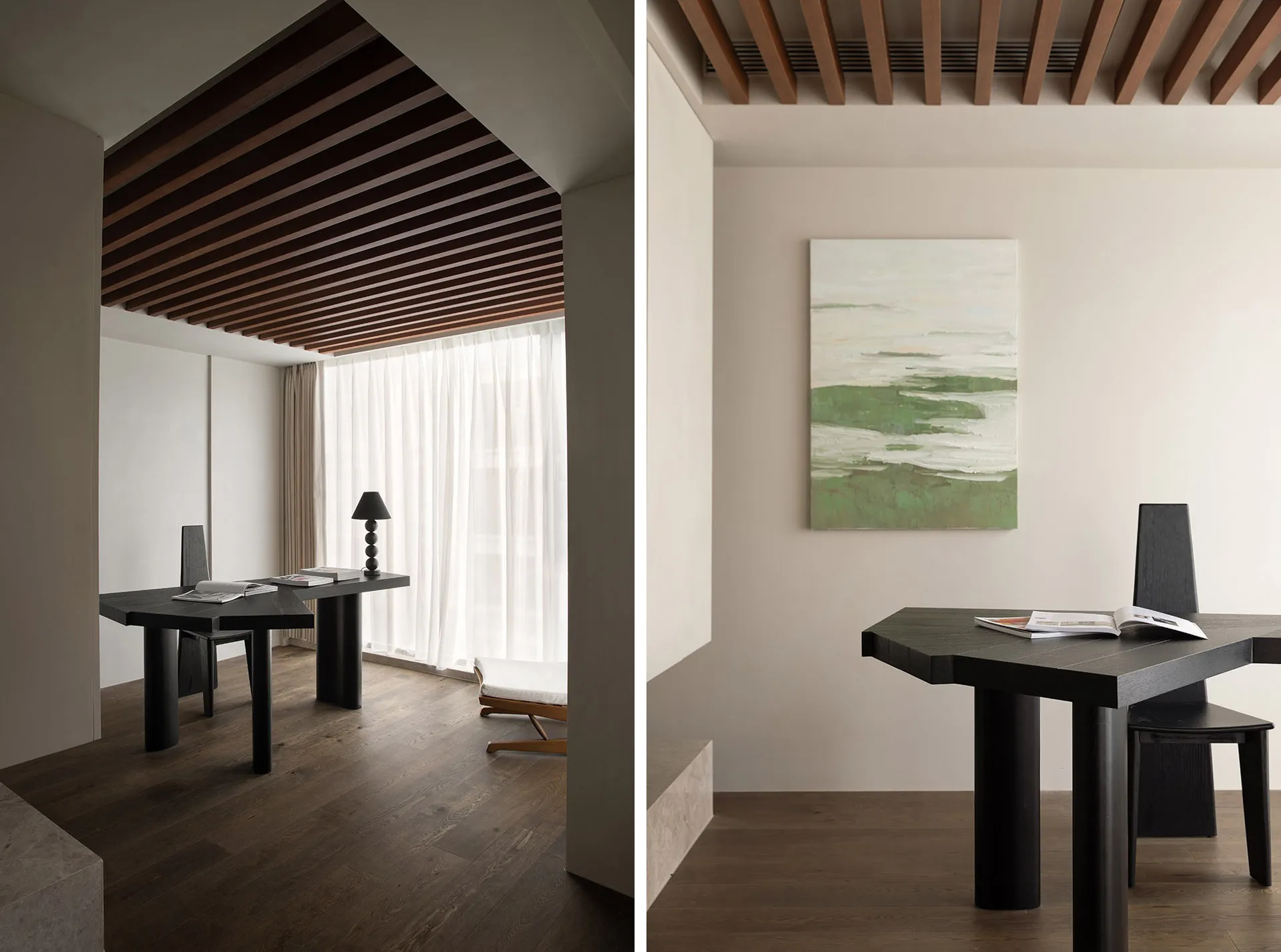 A minimalist home office space featuring black furniture, wooden ceiling beams, and a window with white curtains.