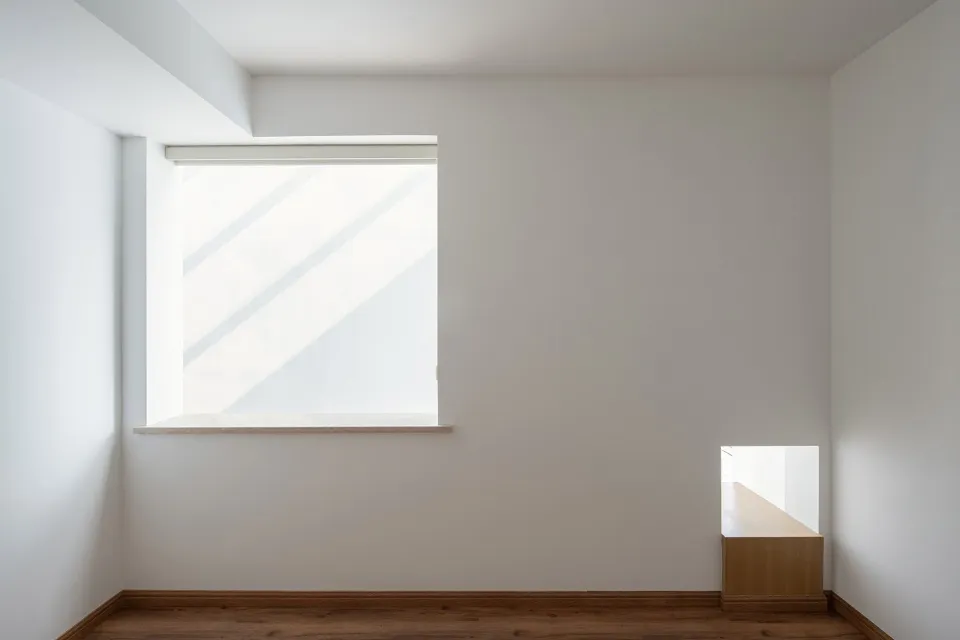 A minimalist room with a large window and a wooden floor.