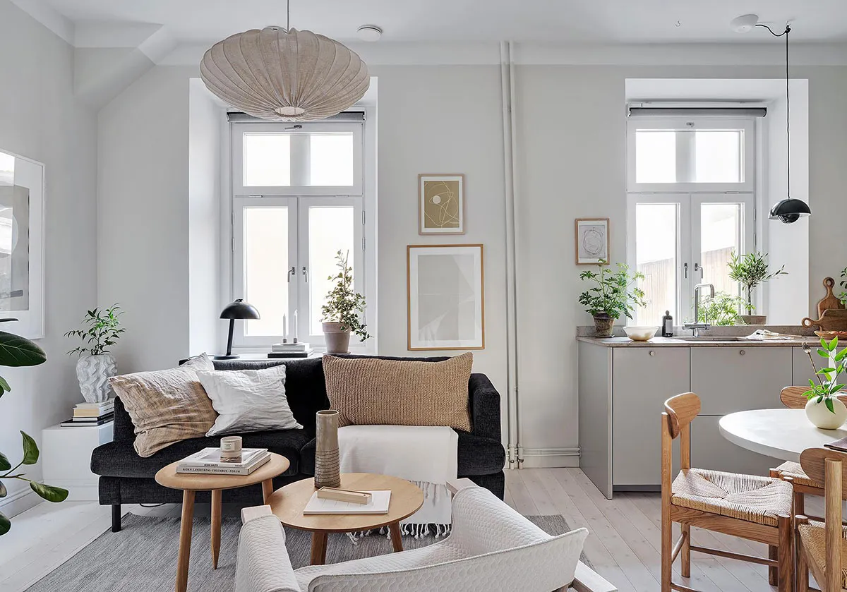 Modern minimalist living room featuring a black sofa, wooden coffee table, and white accent chairs.