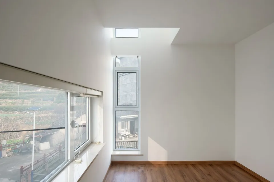 Minimalist white interior design with large windows and a skylight.