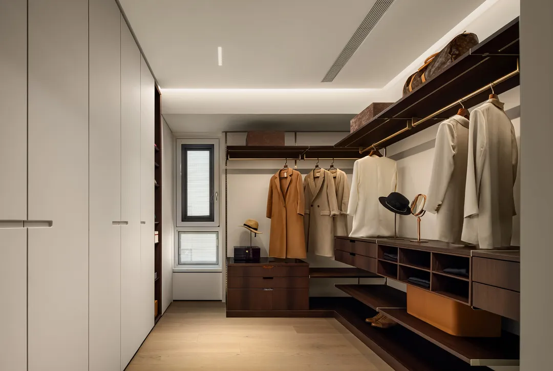 A modern closet with wooden shelves, hanging clothes, and a window.