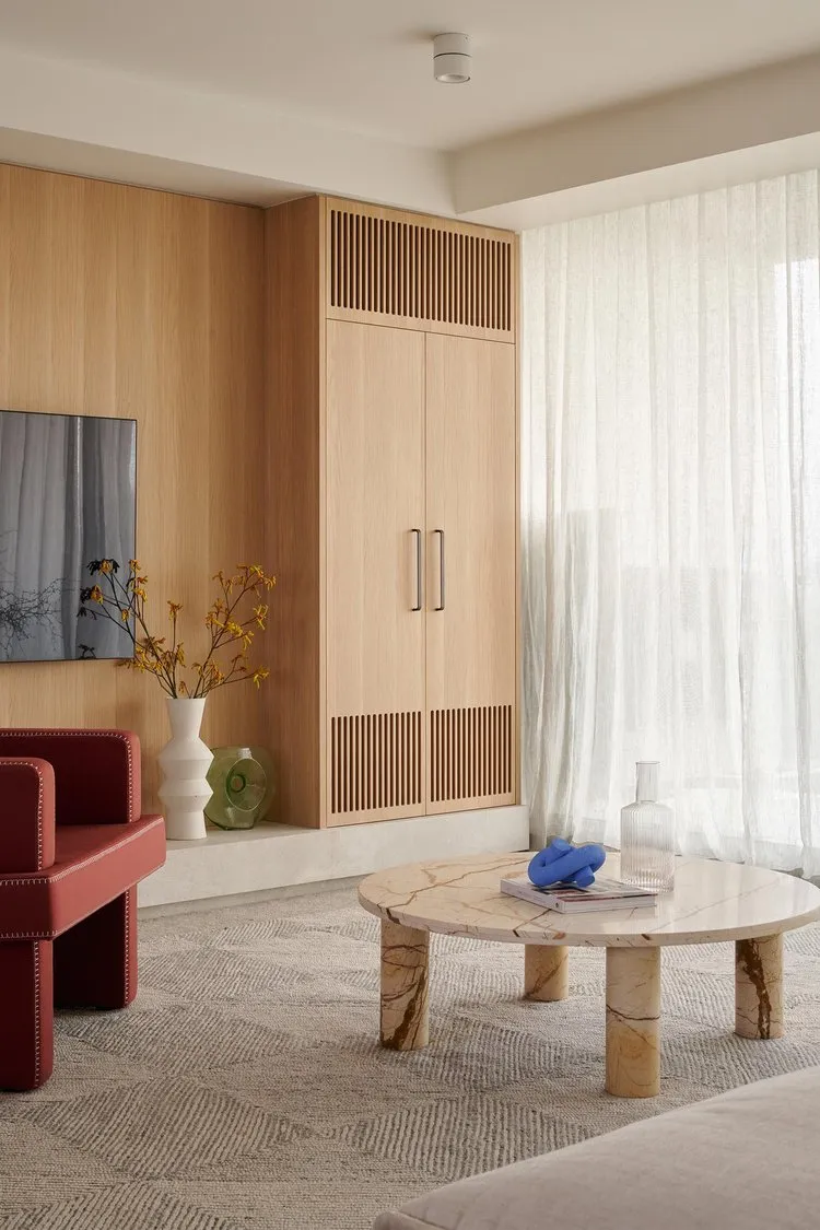 Modern living room with wooden cabinets, marble coffee table, and glass vase.