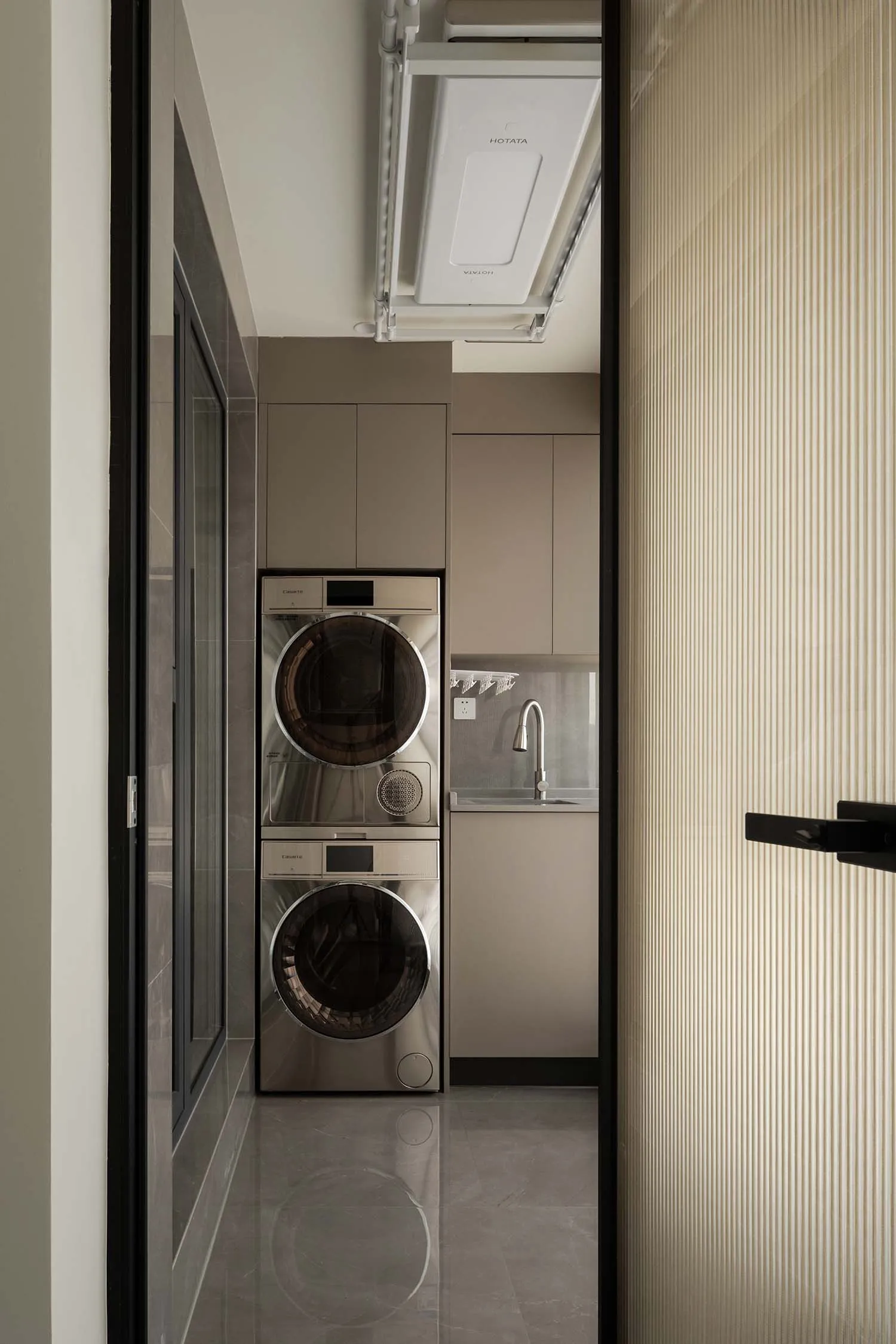 A modern minimalist laundry room featuring metallic appliances.