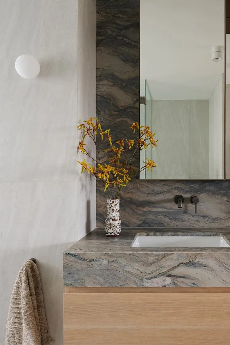 Modern minimalist bathroom featuring marble countertop and black fixtures.