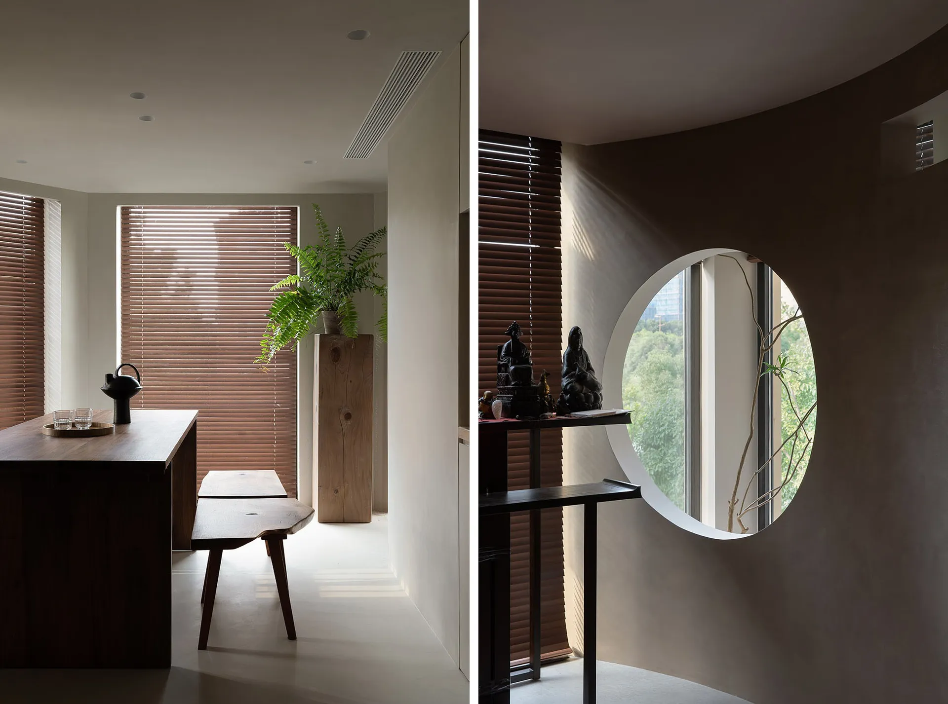 A minimalist living space features a wooden table, bench, and plant under brown blinds, with a circular window and additional