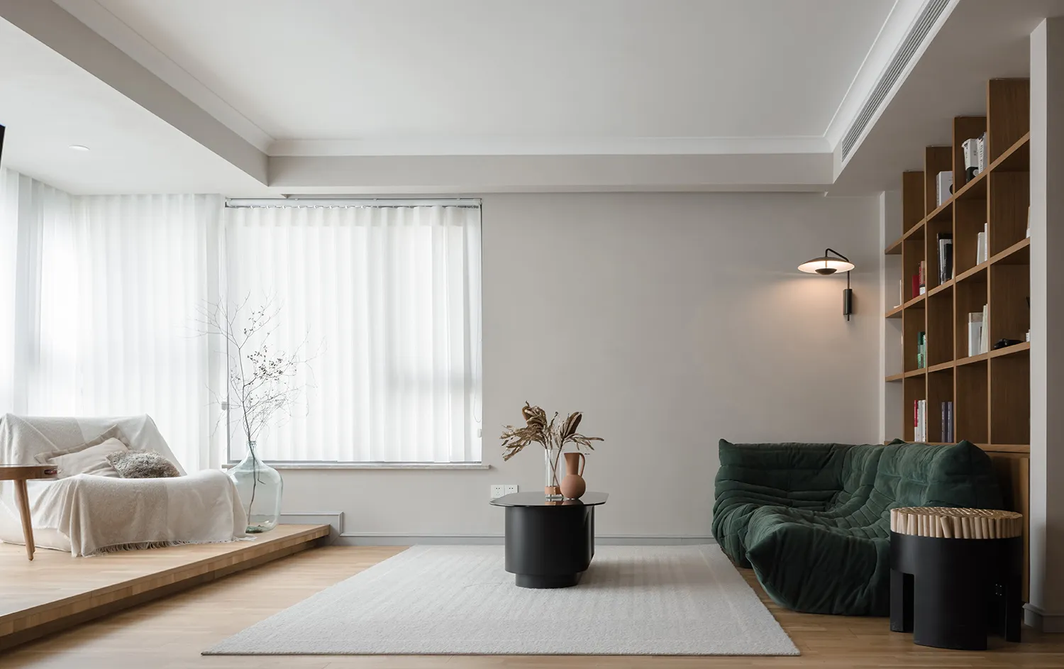 Modern minimalist living room with white sofas, wooden floor, and black coffee table.