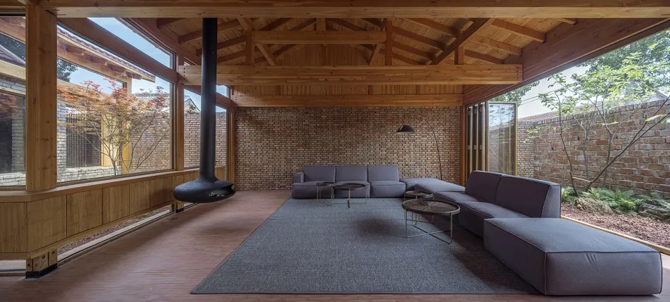 A spacious living room featuring dark wood flooring, a brick wall, and contemporary furniture.
