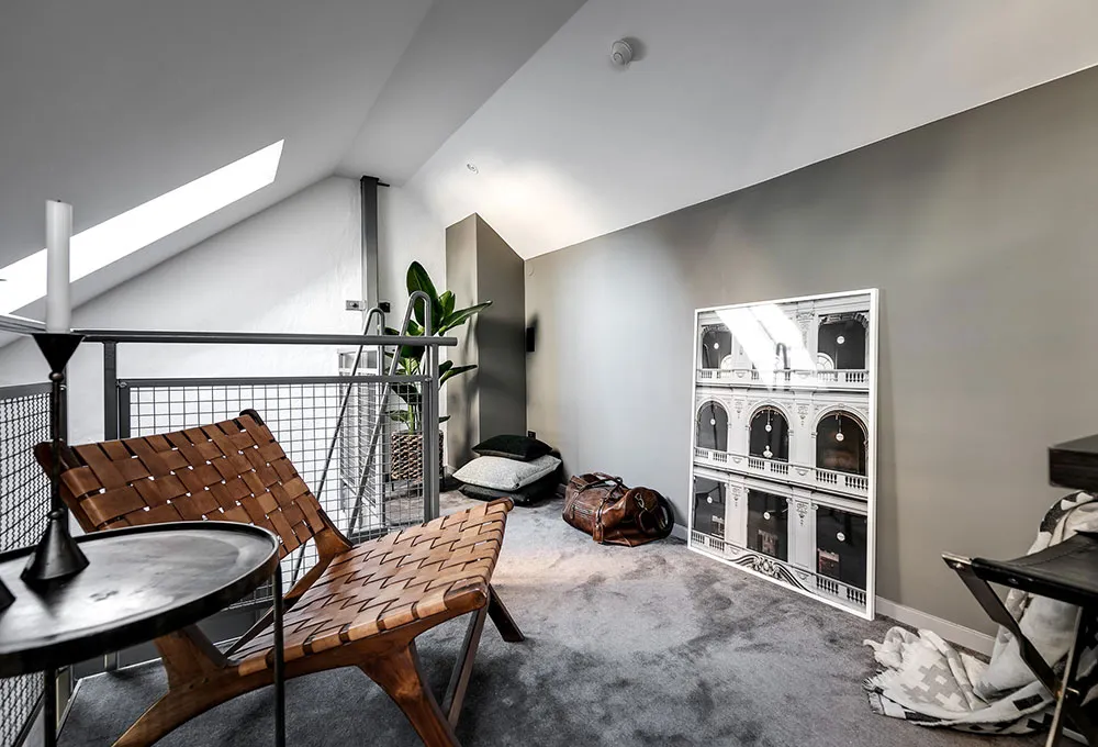 A minimalist living space with wooden furniture and a large framed architectural print on the wall.