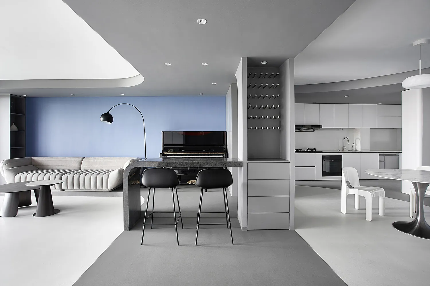 A modern living room with a concrete floor, black and white color scheme, and a piano.