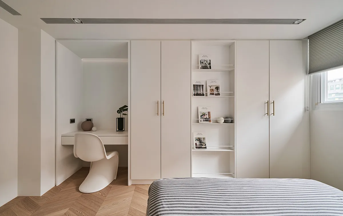 A minimalist bedroom featuring modern furniture with a bed and large closet.