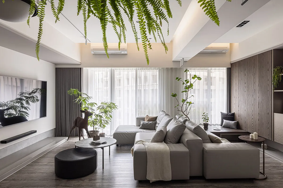 Modern, minimalist living room featuring contemporary furniture, wood floors, glass elements, and a variety of plants.