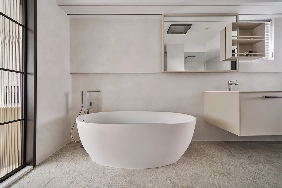 A modern minimalist bathroom with a freestanding bathtub, concrete walls, and floor tiles.