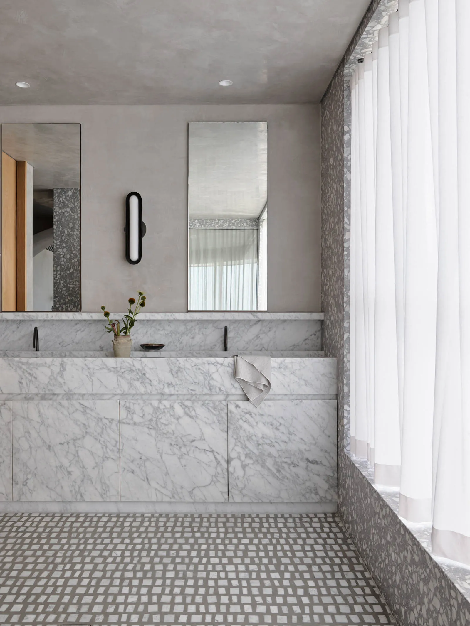 Modern bathroom featuring marble countertops and floors with a white curtain on the right side.