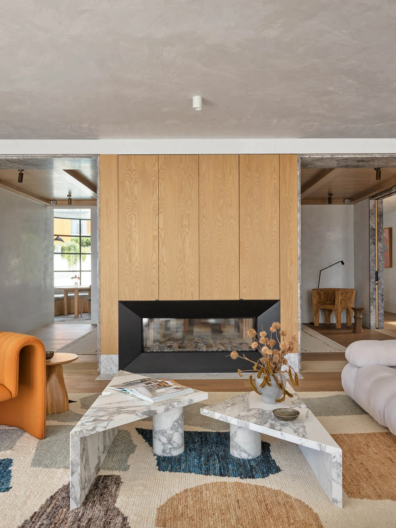 Modern living room featuring marble tables and a fireplace with wood panels.