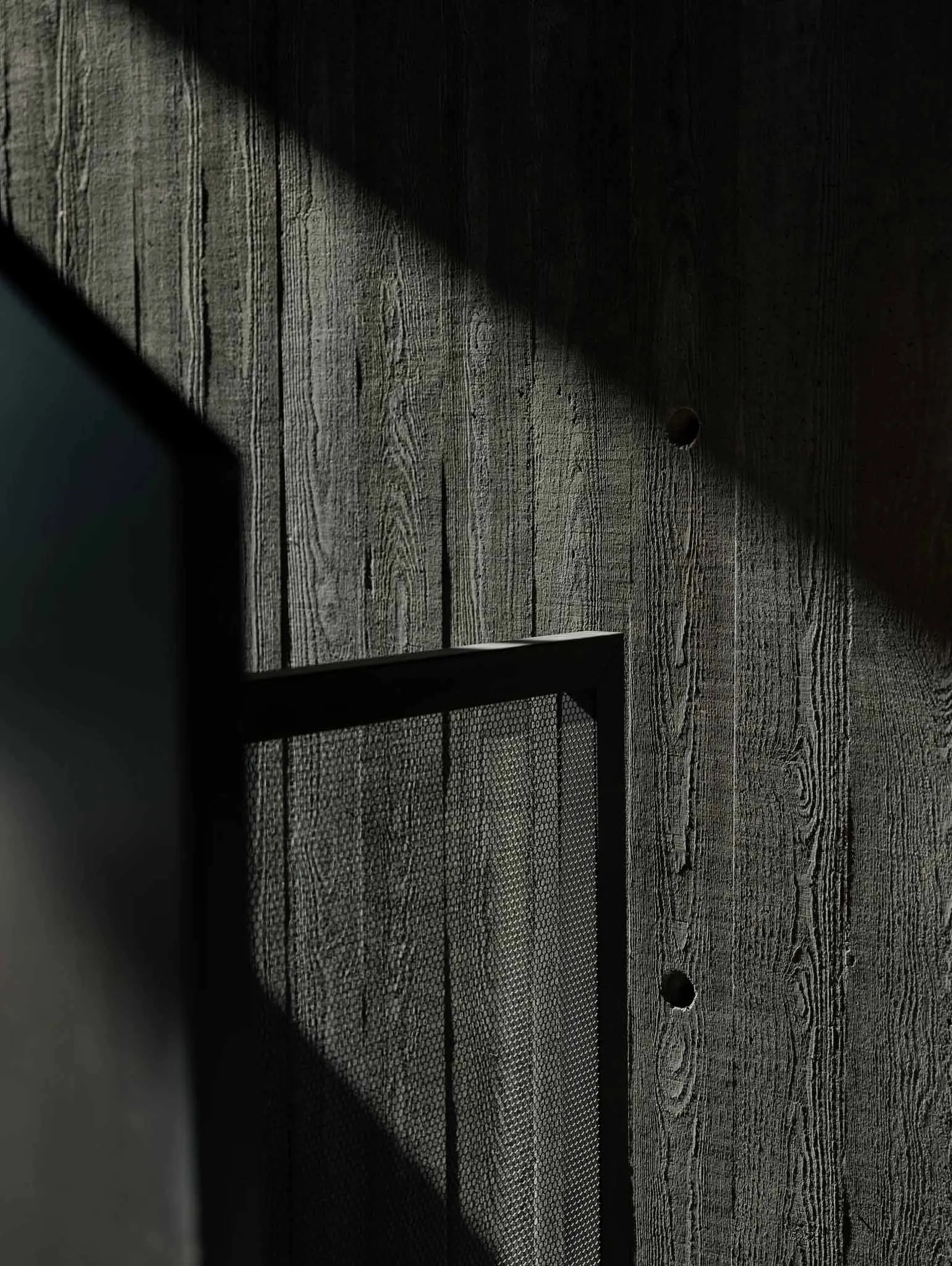 A wooden wall with a window, showcasing industrial aesthetics in black color.