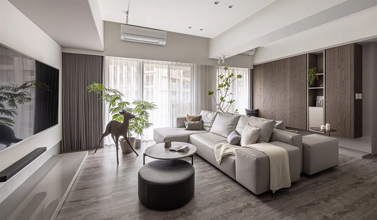 A modern living room with a gray sectional sofa, potted plants, and minimalist decor.
