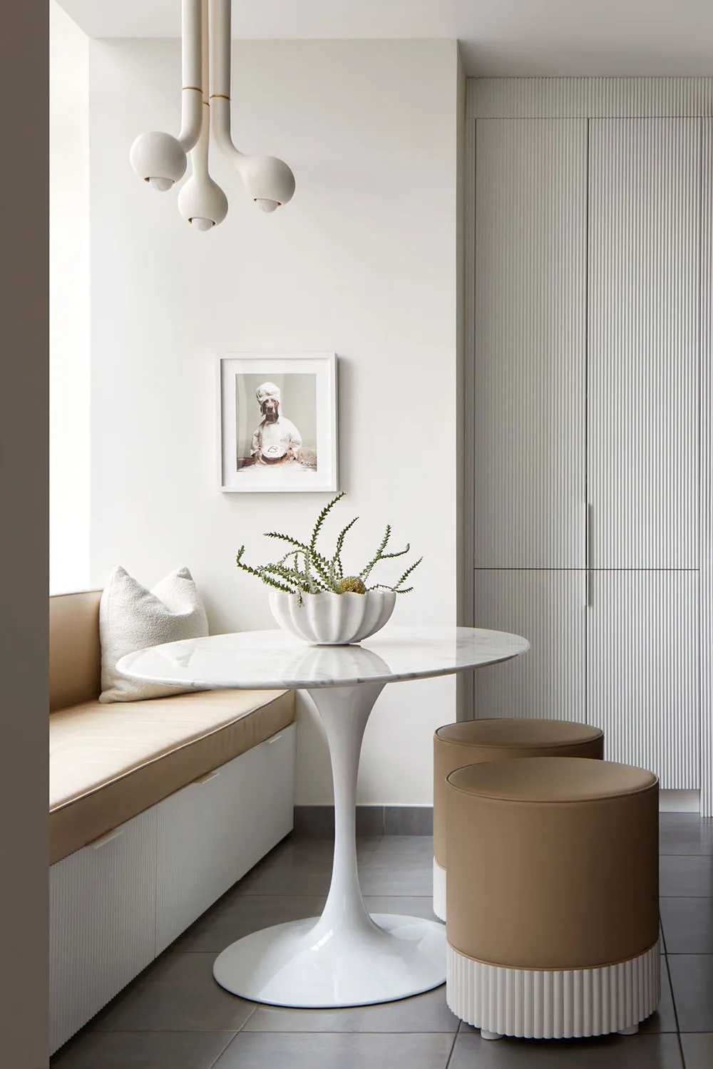 Modern kitchen area featuring a sleek, white marble table with a concrete base surrounded by comfortable seating, perfect for
