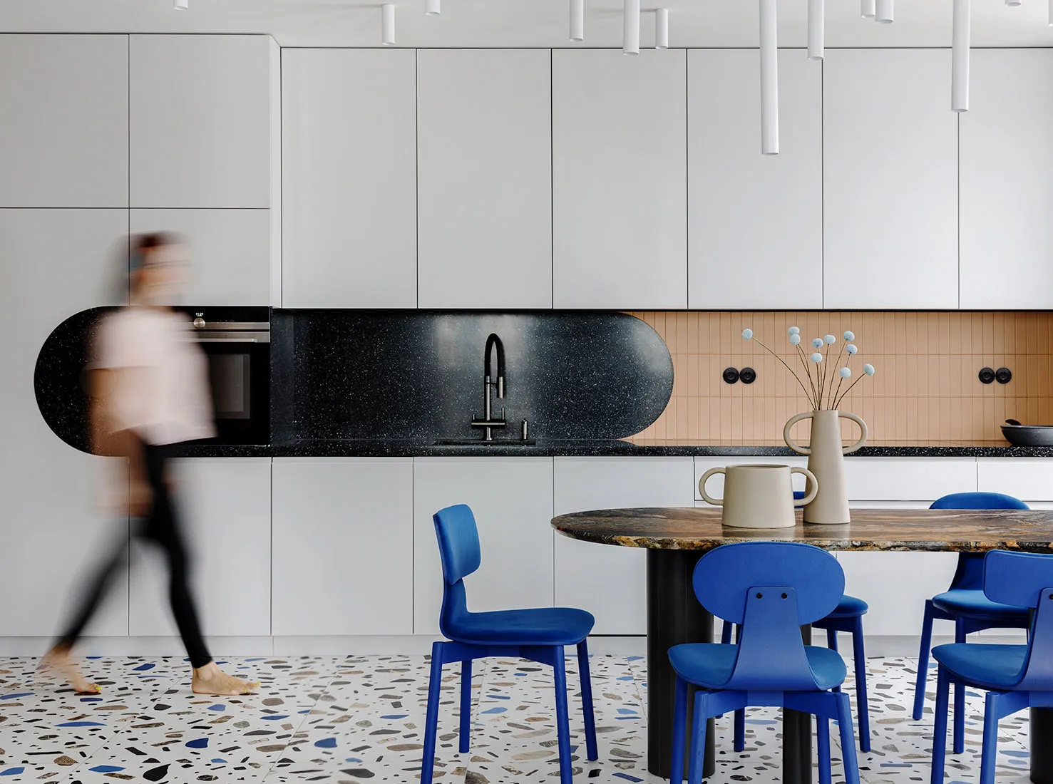 A modern kitchen with a black granite countertop and a terrazzo floor.