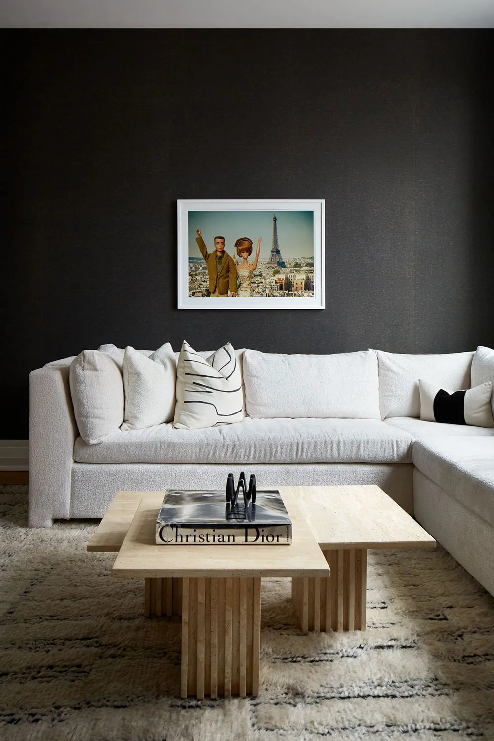 A living room with a white sectional sofa, a wooden coffee table with a book and decorative items, and a framed photograph of