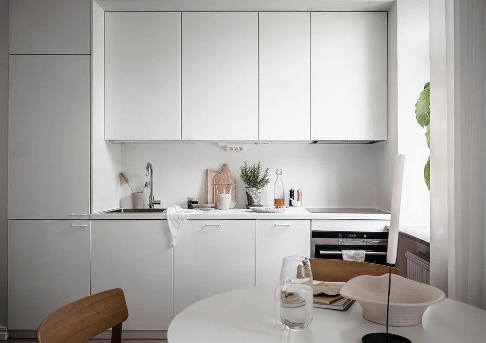 A minimalist white kitchen with modern cabinets and a clean, uncluttered design.