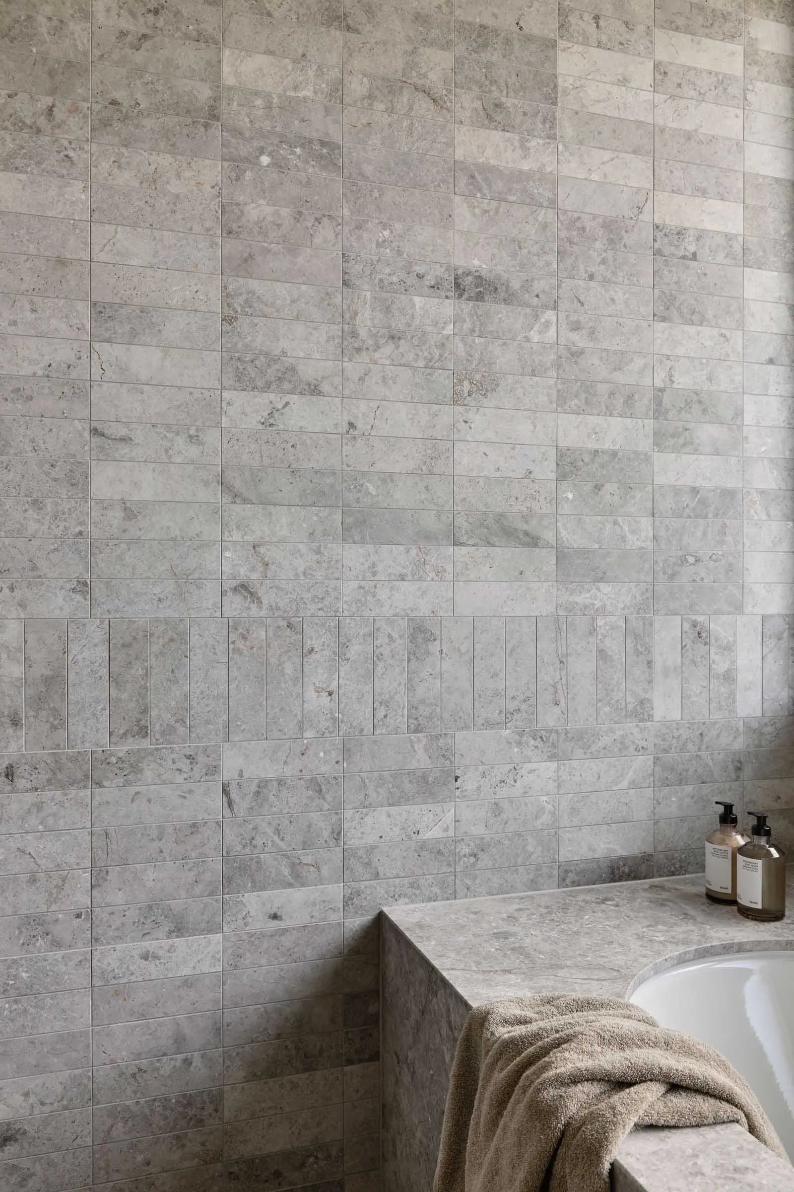 Modern minimalist bathroom with stone tile walls and a clean, uncluttered design.